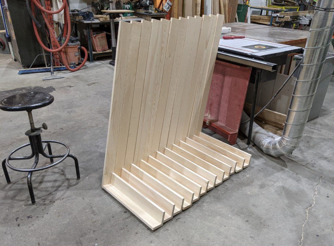 twelve L-shaped corners of the panels stacked together leaning on a table saw in a wood shop